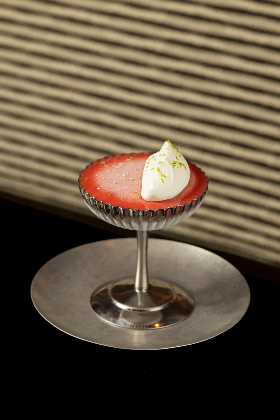 Plum sorbet with lime zest and cream in a silver coupe