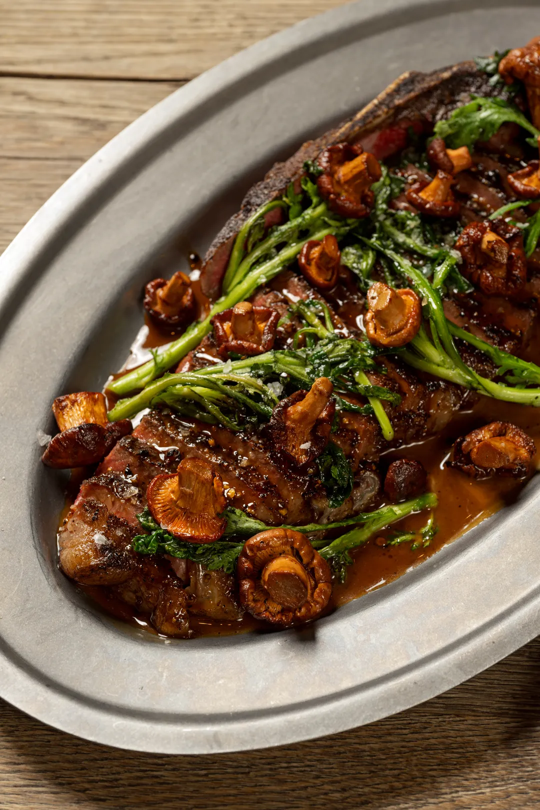 Grilled bone-in strip steak with chanterelles and greens